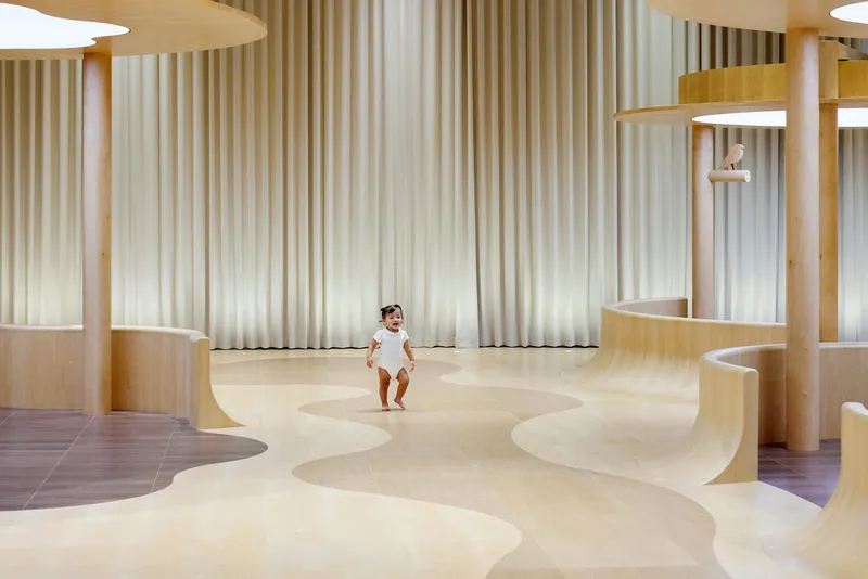 Young child running across the undulating plywood floor beneath fabric curtain walls and circular columns