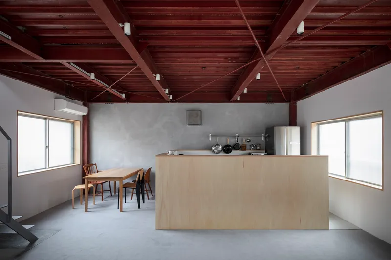 Open kitchen and dining area beneath an exposed dark timber beam ceiling with white walls