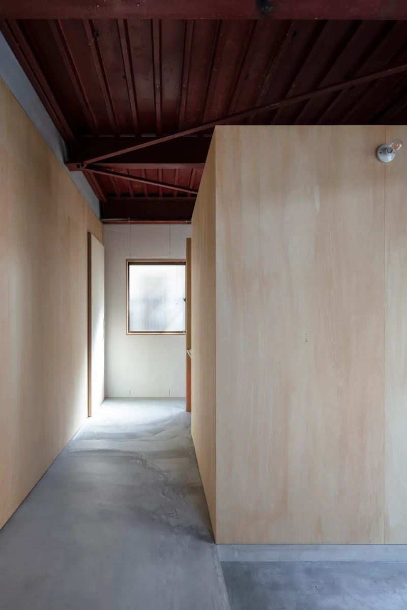Hallway with exposed reddish-brown timber roof beams and polished concrete floor