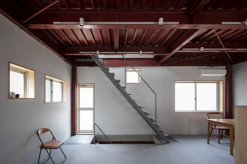 Room with diagonal steel stair crossing beneath exposed timber joists and track lighting