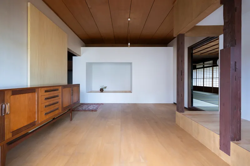 Interior room with timber ceiling, exposed wood columns and a wall niche opposite a doorway to tatami space