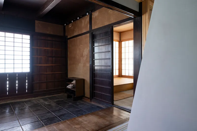 Entrance vestibule with dark stone tile floor and sliding timber door opening to tatami room with paper screens