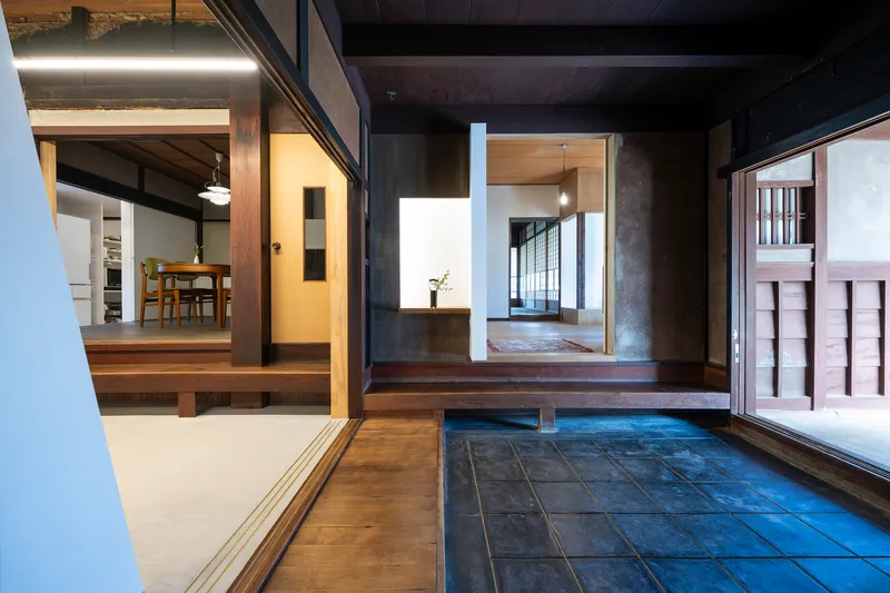 Tiled entrance vestibule with dark timber framing opening to illuminated interior rooms beyond