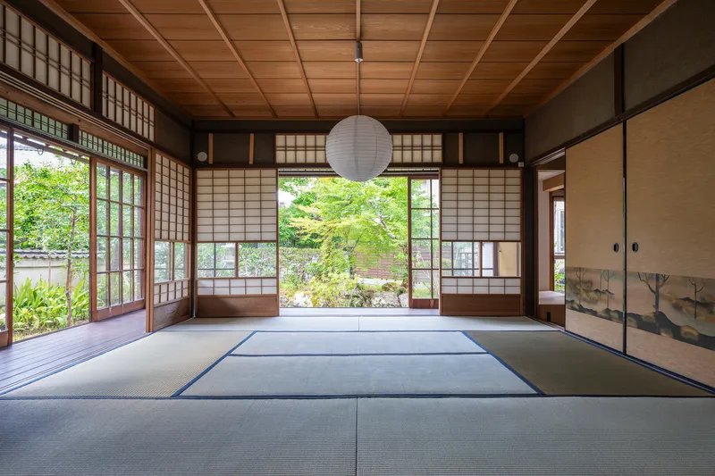 Tatami mat room with coffered timber ceiling and sliding shoji screens facing a garden courtyard