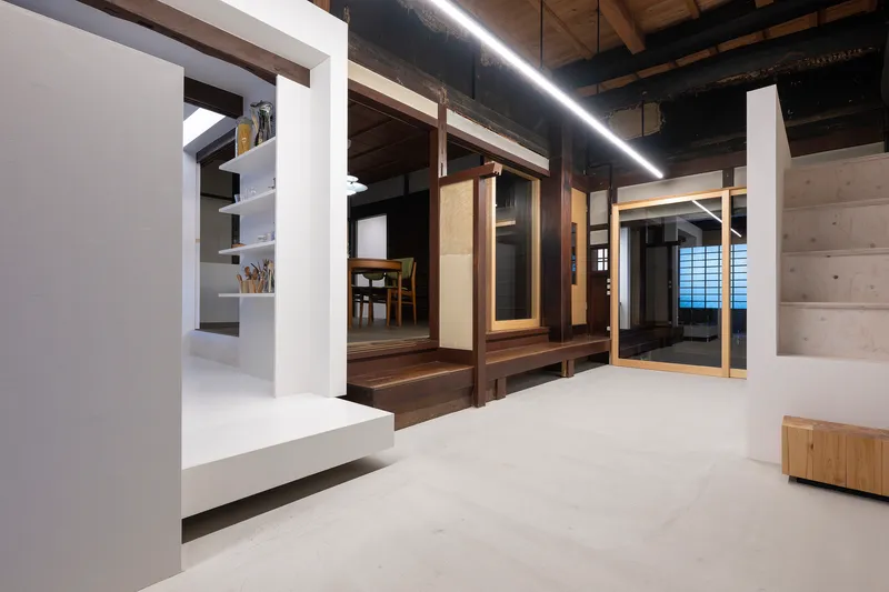 Interior hallway with white partition walls contrasting dark timber framing and exposed ceiling beams