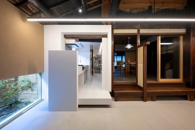 View through doorway to kitchen with exposed timber framing and raised dining platform at dusk