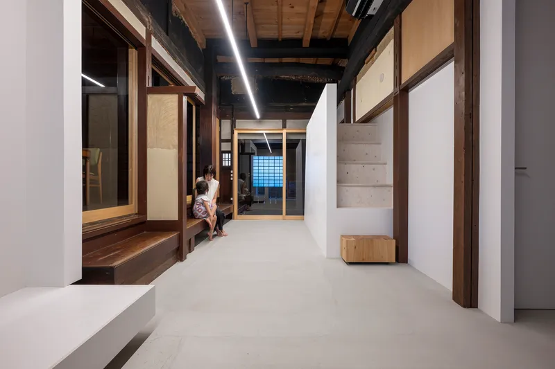 Hallway with two people sitting on timber bench beneath continuous linear ceiling fixture