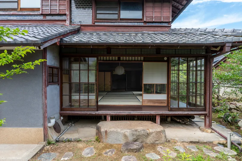 Exterior view of sliding glass doors opening onto raised timber veranda with tiled roof above