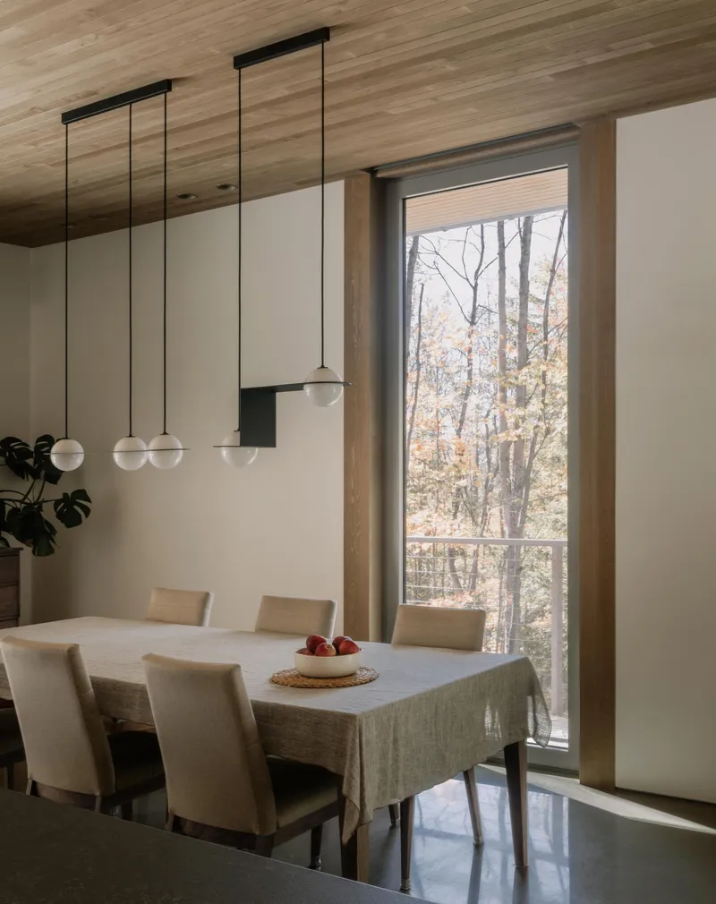 Dining area with pendant lights and tall window framing bare trees