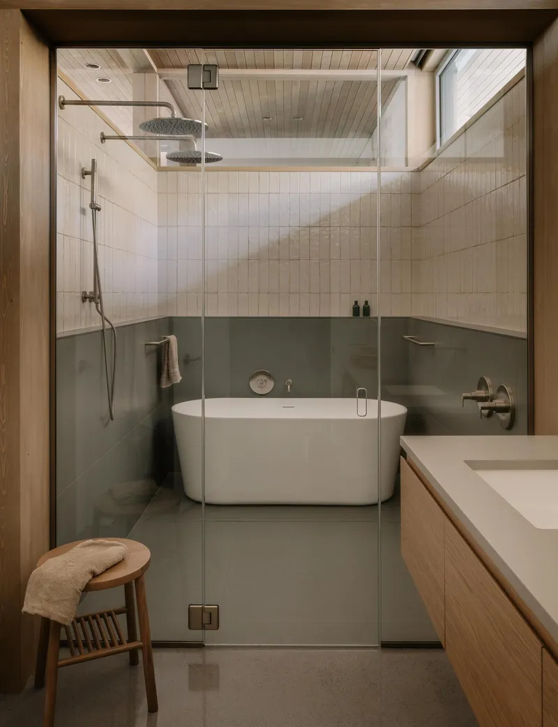 Bathroom with freestanding white tub, olive-green tile wainscoting and glass-enclosed shower with overhead rainfall fixture