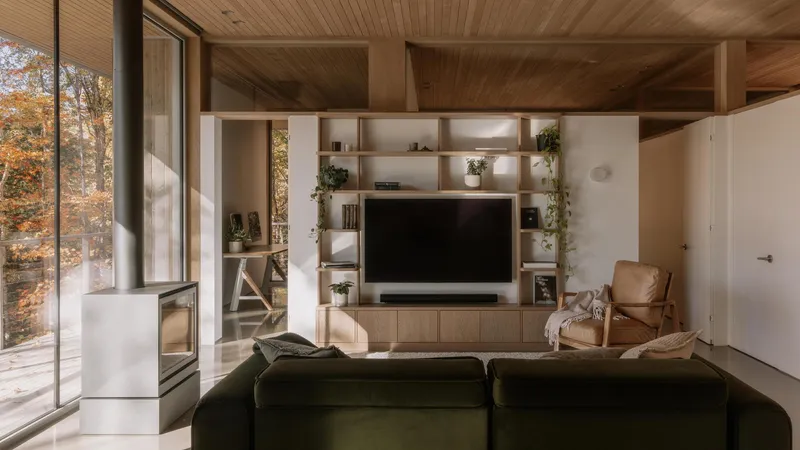 Living room with built-in shelving unit beneath exposed timber ceiling and full-height windows