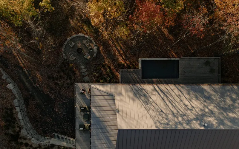 Aerial view of standing seam metal roofs nestled among deciduous trees in fall foliage