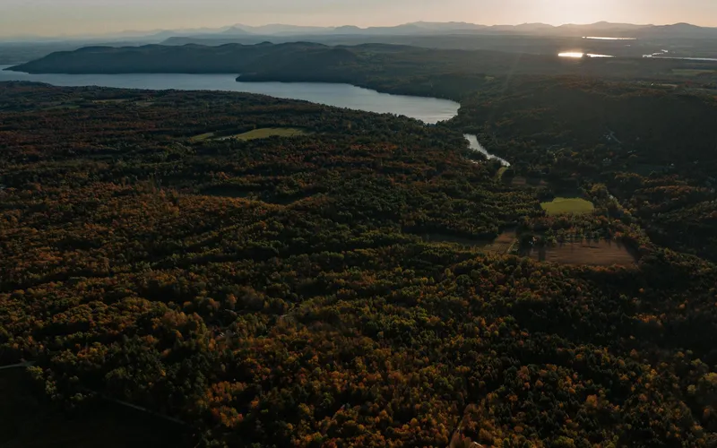 Aerial landscape showing forested hills, lakes, and scattered clearings at dusk
