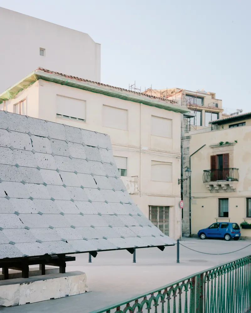 Side view of the tiled canopy against residential buildings with a parked blue car