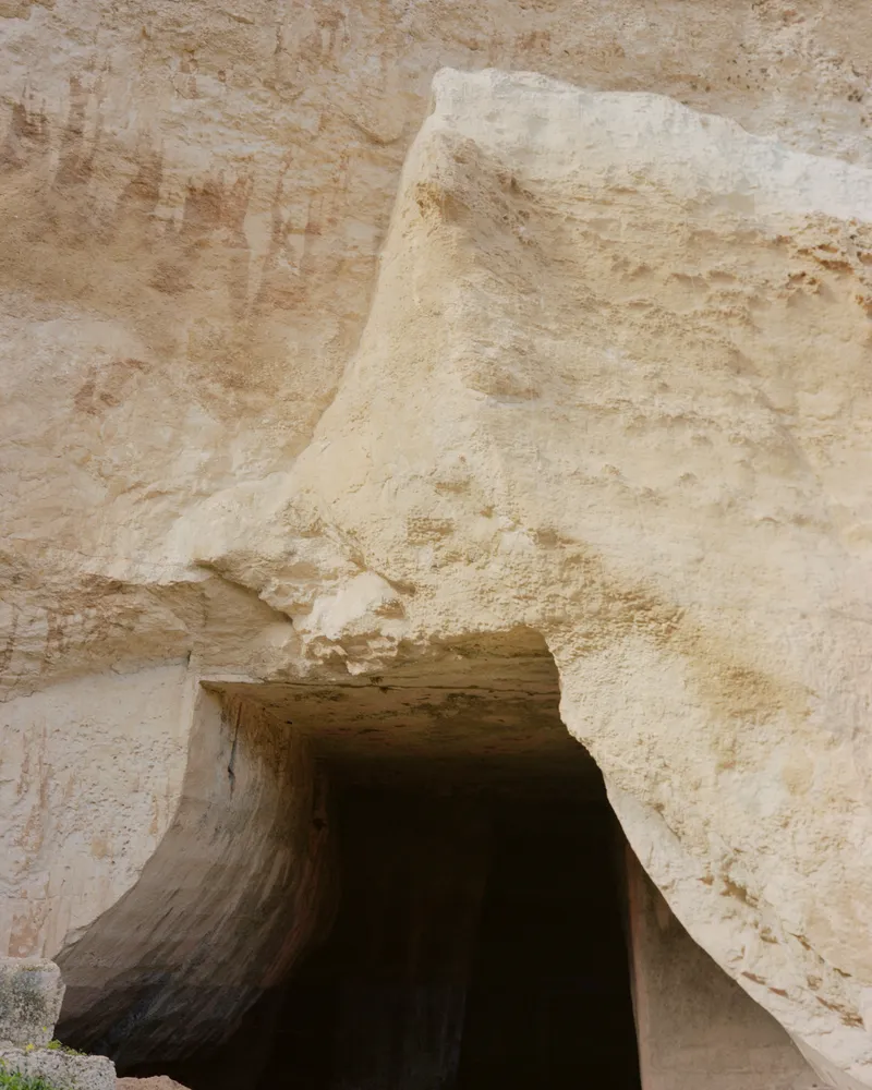 Carved sandstone archway opening into a shadowed interior passage with weathered walls