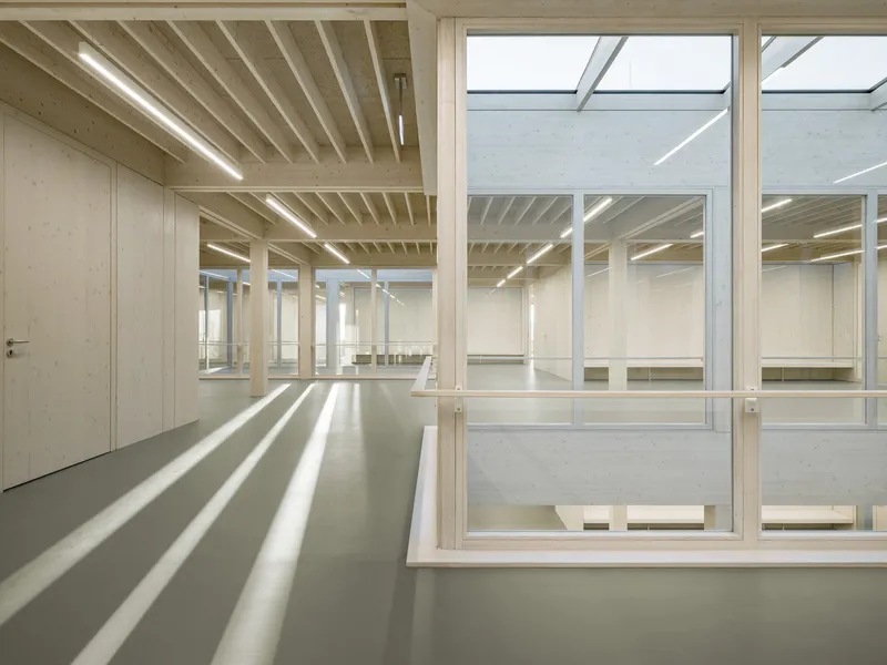 Glass-walled interior courtyard surrounded by timber columns and strip lighting overhead