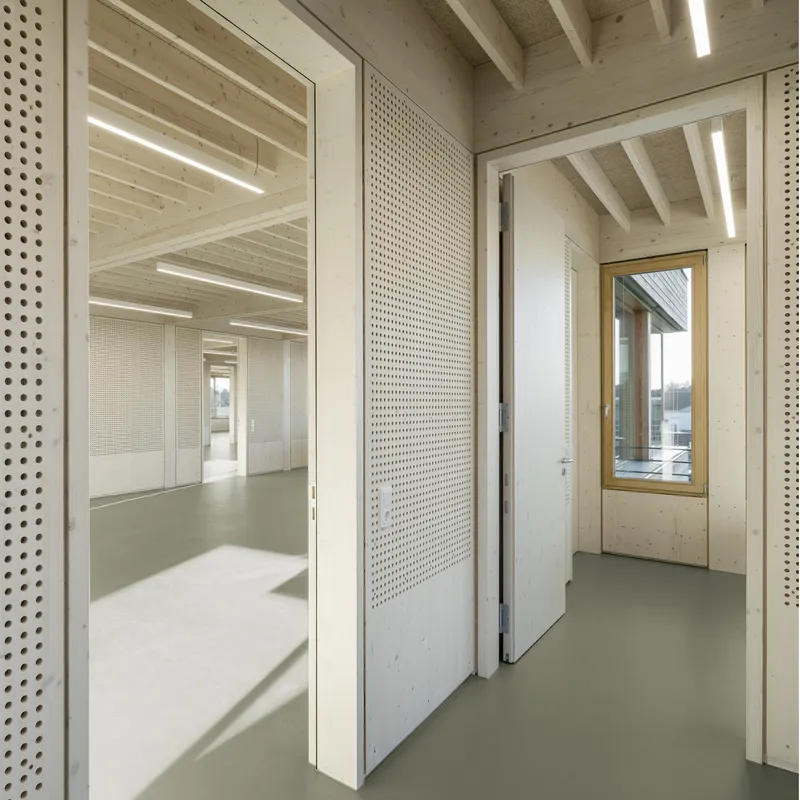 Interior threshold showing perforated white panel door between timber-framed spaces with resin flooring