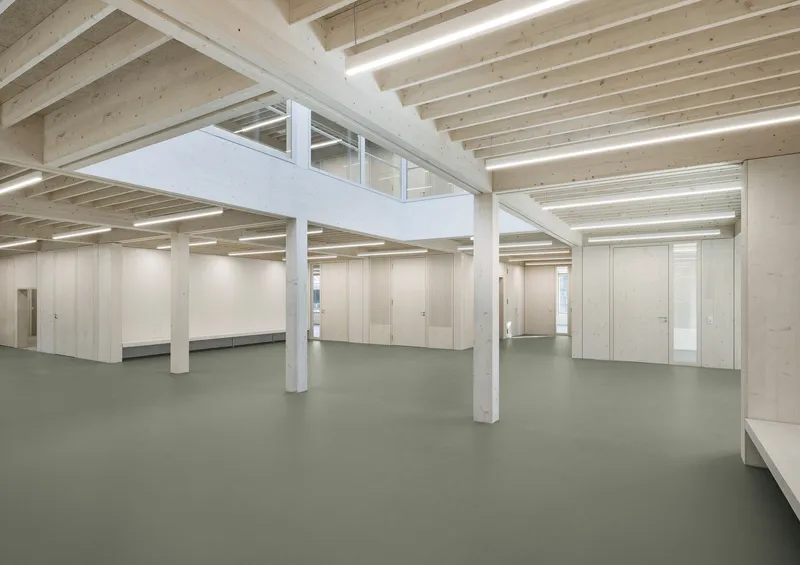 Mezzanine platform with glazed balustrade above an open workspace with timber joists and columns