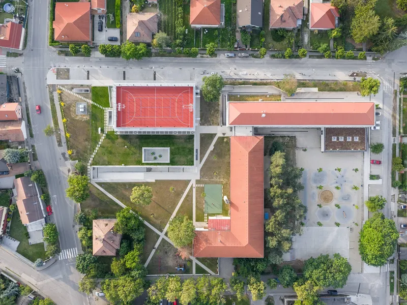 Aerial view of the campus showing terracotta roofs, sports court, diagonal pathways and courtyard below