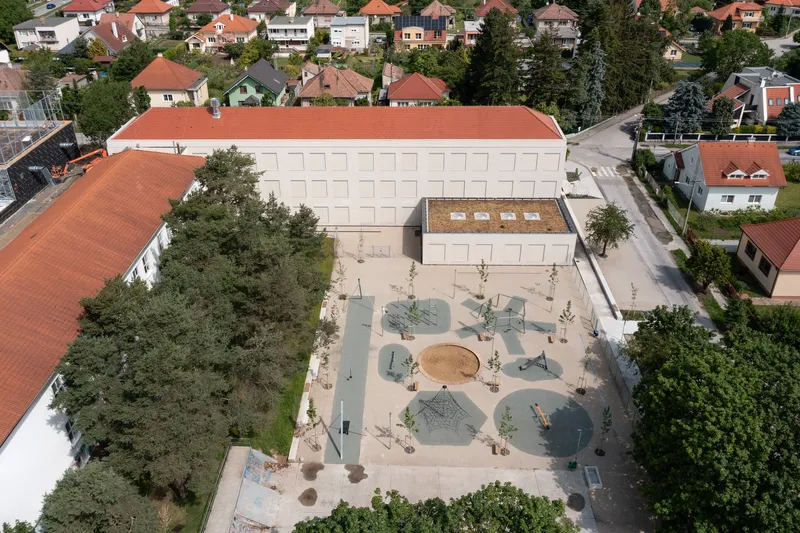Aerial view of the courtyard with circular play zones, young trees and benches arranged on pale paving