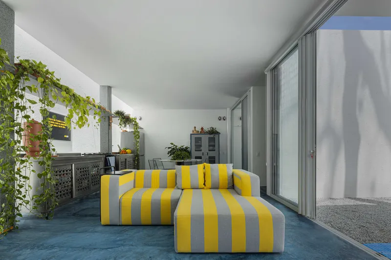 Covered terrace with blue floor, yellow and grey striped seating and sliding glass doors