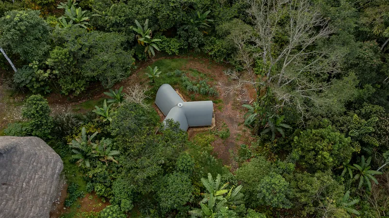 Aerial view of the grey vaulted roof nestled into a clearing surrounded by tropical vegetation