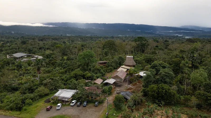 Drone view of the compound with vaulted roofs emerging from dense rainforest at dusk
