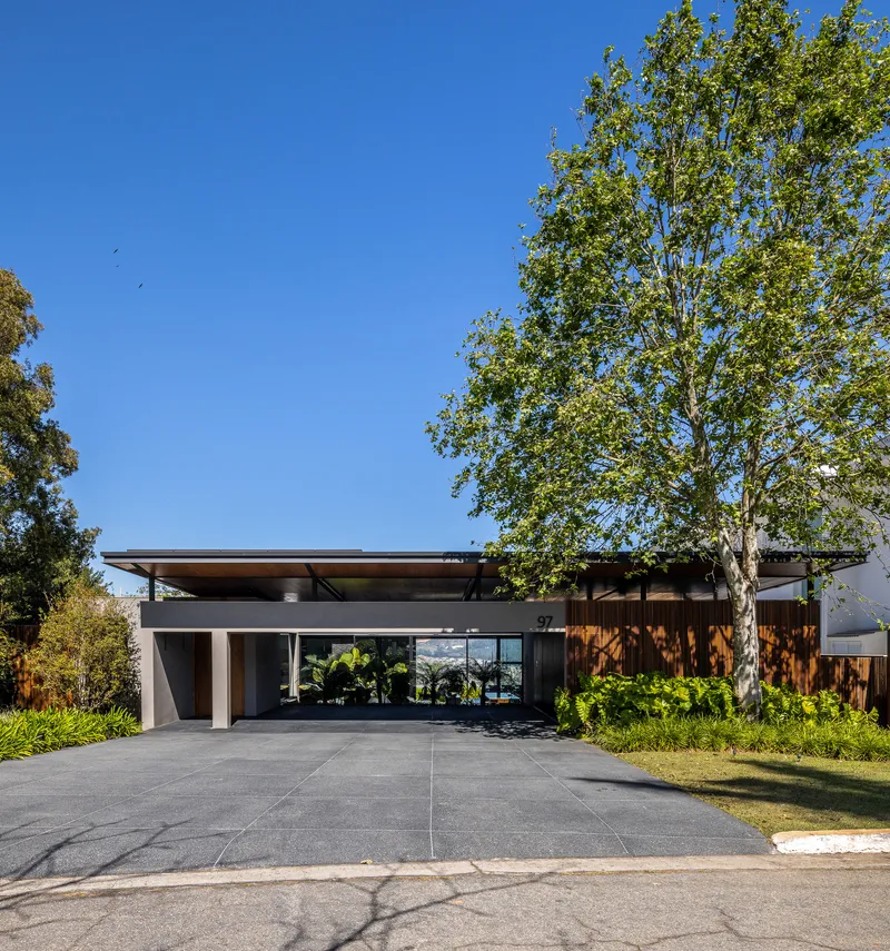 Street view of the horizontal roofline with wide eaves sheltering a forecourt under clear blue sky