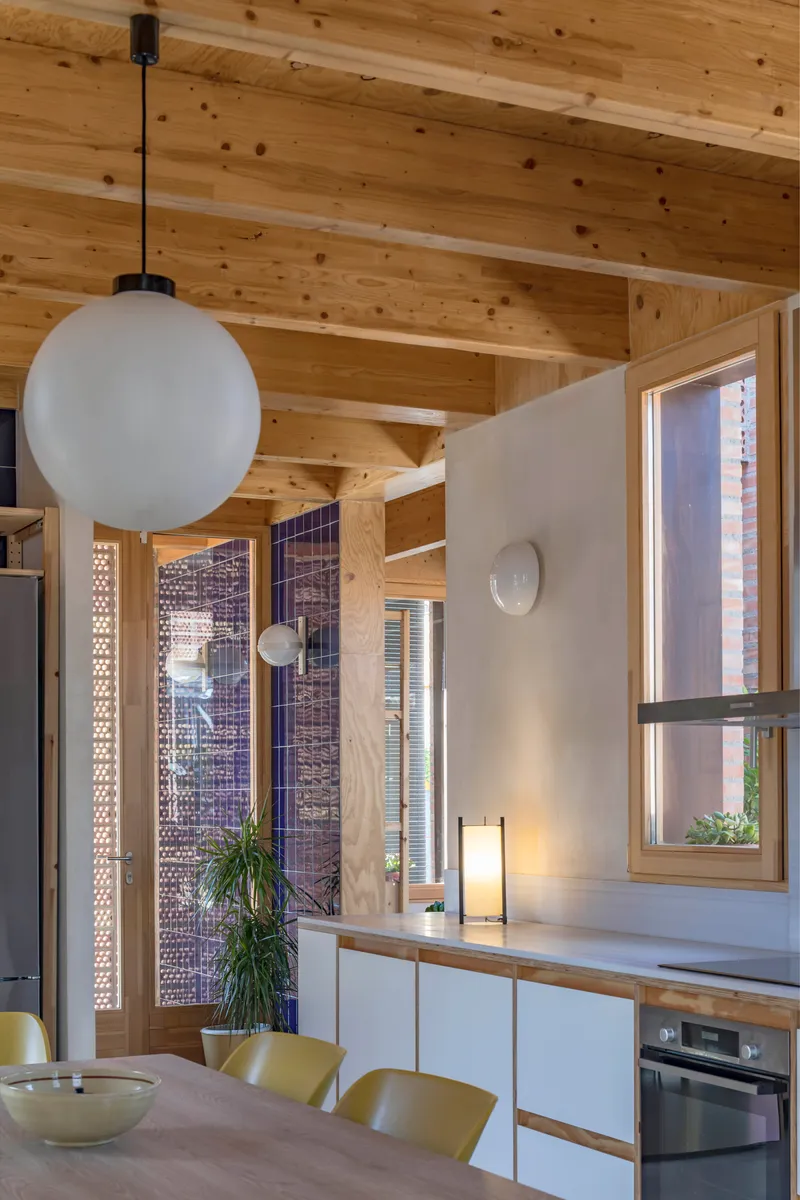 Dining area with spherical pendant light under exposed timber beams and perforated brick screens beyond