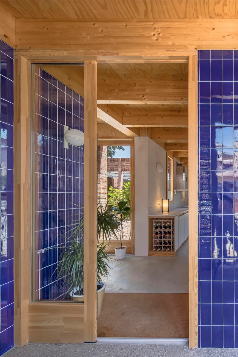 Timber-framed entrance with blue glazed tile walls and potted plants in the interior hallway