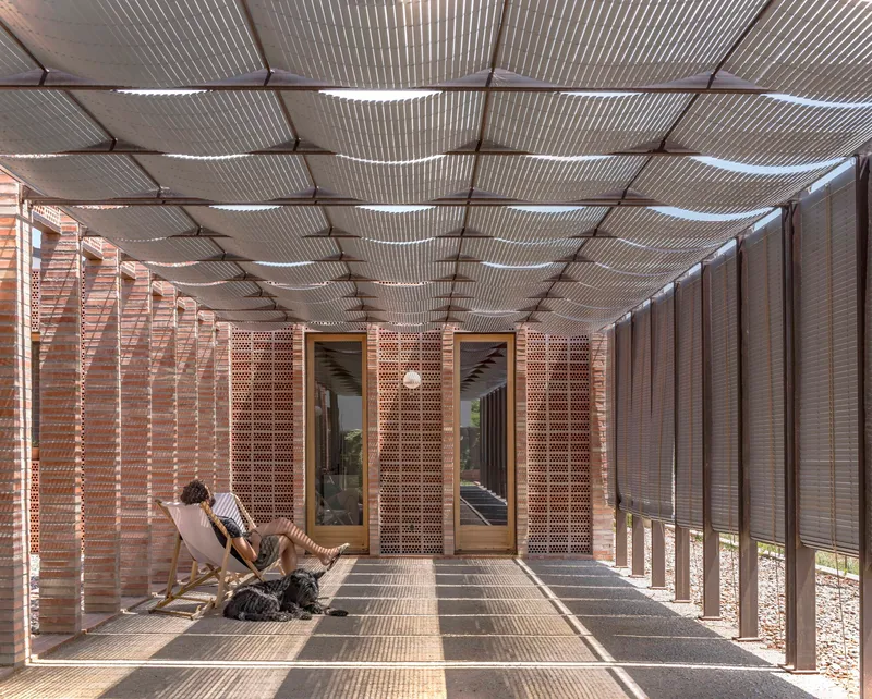 Covered porch with corrugated metal ceiling and perforated brick screens filtering afternoon light