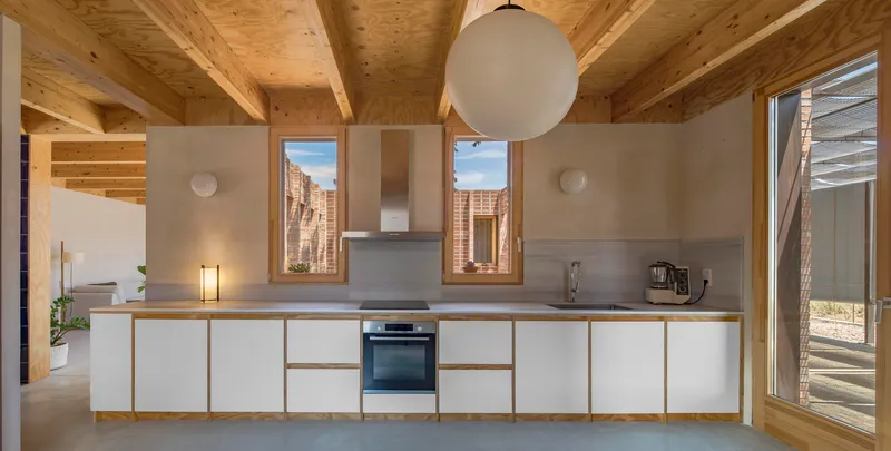 Kitchen with white cabinetry beneath an exposed timber beam ceiling and pendant light