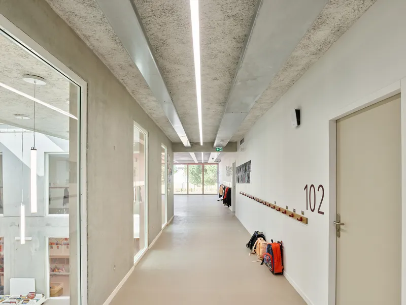 Upper-level corridor with glazed balustrade overlooking the atrium and coat hooks along the white wall