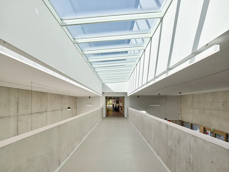 Upper level circulation hallway with cast concrete walls and a continuous glass skylight overhead