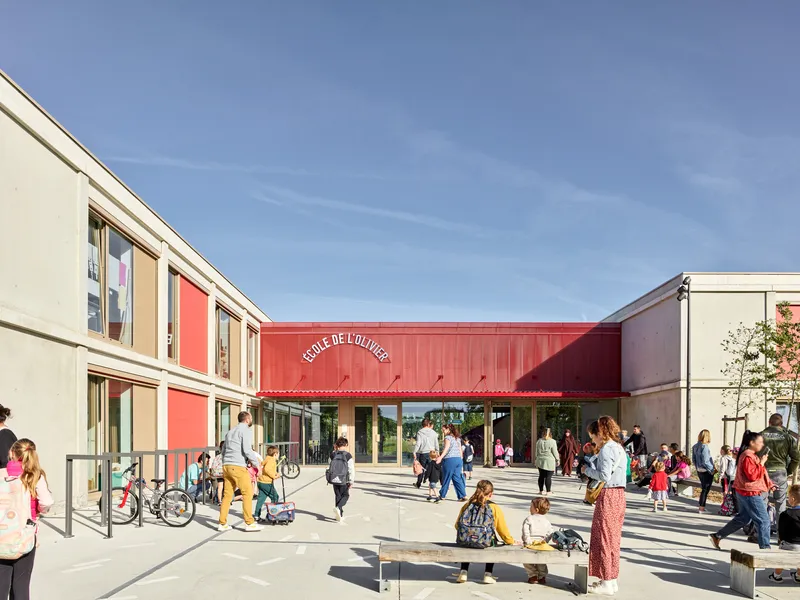 School courtyard with red metal canopy and families gathering at dismissal time