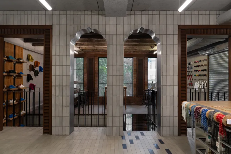 Twin arched doorways in tiled walls revealing timber interior and tree-lined windows beyond metal railings