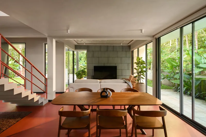 Open-plan dining area with timber table and floor-to-ceiling glazing overlooking planted garden