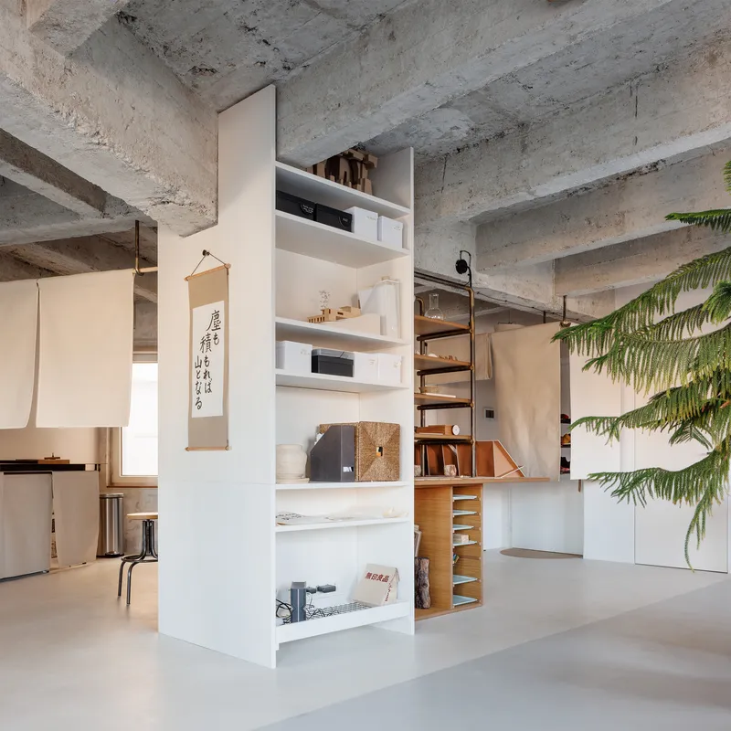 Freestanding shelving unit dividing the open floor plan with exposed concrete waffle ceiling above