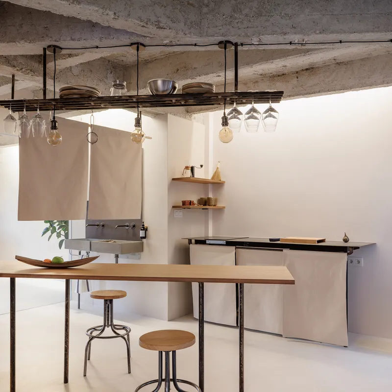Kitchen counter with hanging glassware rack and pendant bulbs suspended from the concrete ceiling