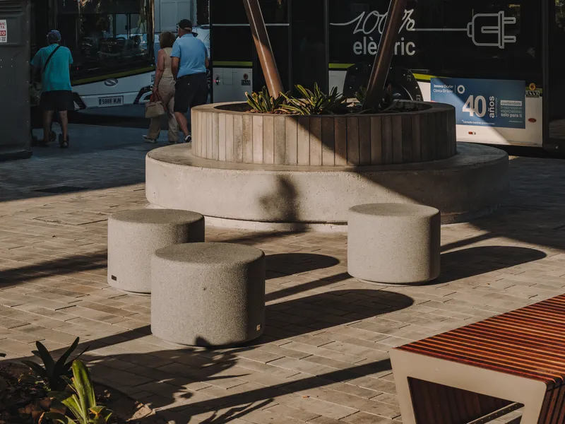 Concrete bench and raised planter casting shadows on paving in morning light