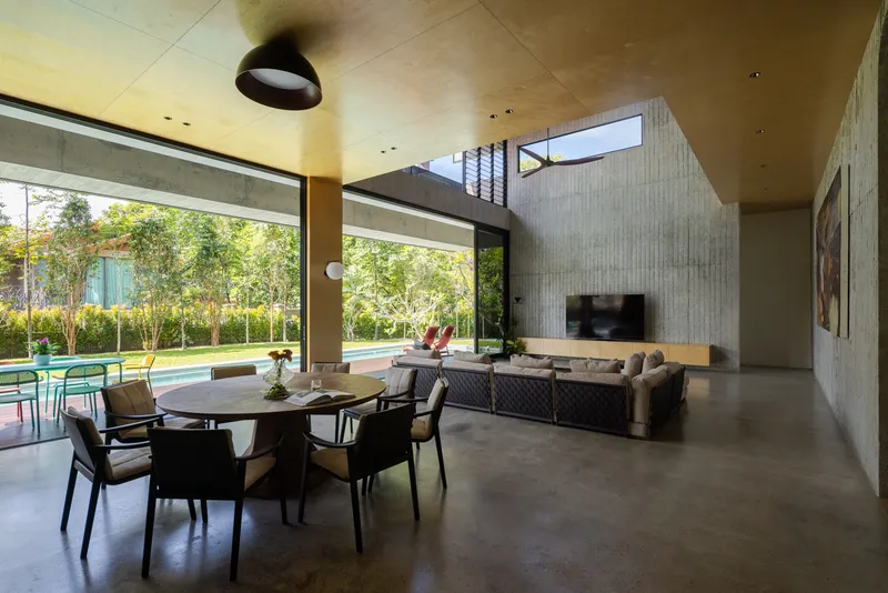 Open-plan living and dining space with polished concrete floor and clerestory light filtering through the garden