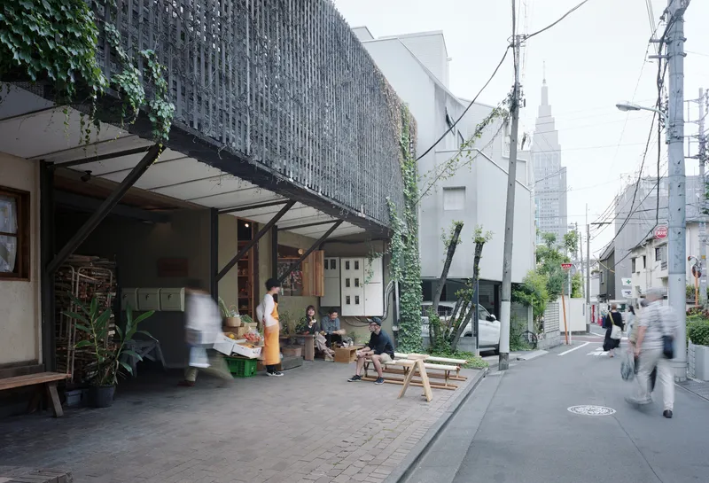 Perforated brick screen facade with steel bracing above a street-level shop terrace