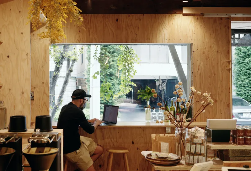 Plywood-lined window counter with a person working on a laptop overlooking the street