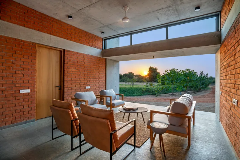 Seating area framed by concrete beam opening with view to landscape at sunset