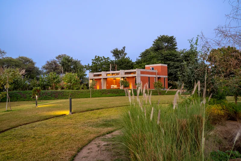 Rear view of the residence across a lawn with ornamental grasses at dusk