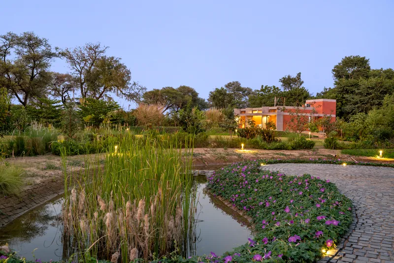 Garden pond with flowering plantings and paved terrace at twilight