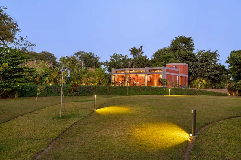 Landscape lighting casting yellow pools across the sloping lawn in early evening