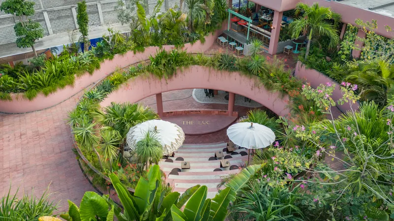 Curved planted walls surrounding the amphitheater steps with white parasols and tropical vegetation