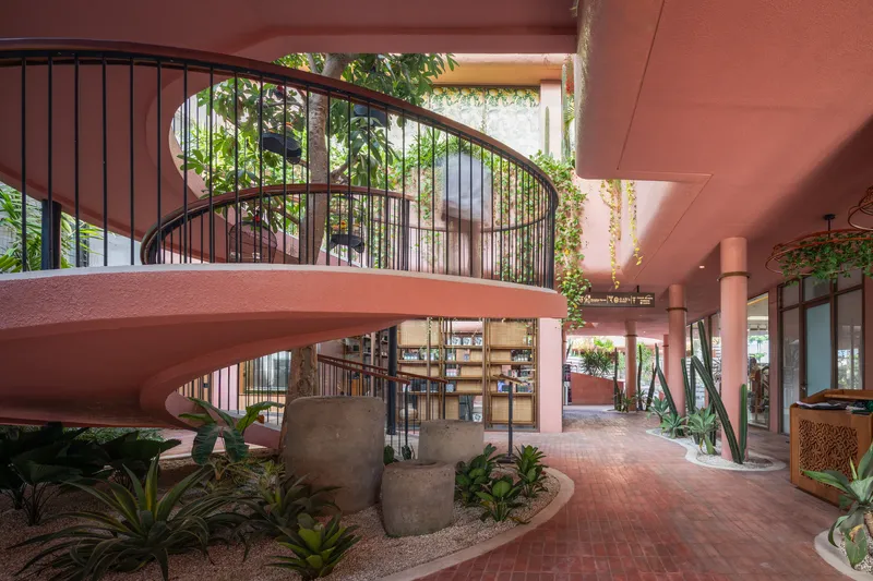 Curved staircase with black metal railings rising from the planted interior courtyard below