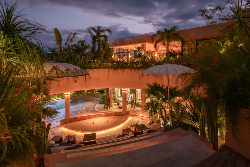 Sunken courtyard with curved seating and planted terraces under evening sky